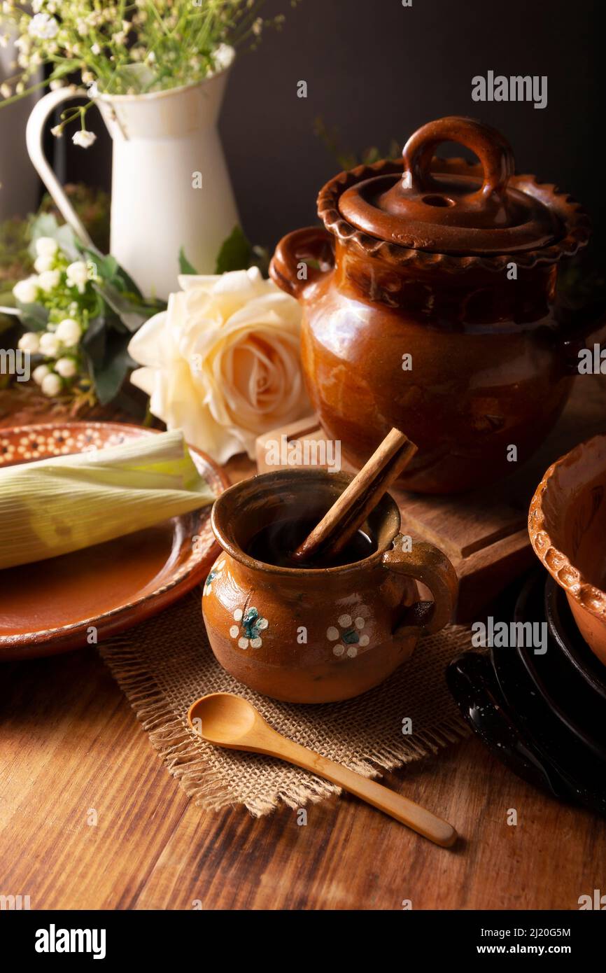 Authentic homemade mexican coffee (cafe de olla) served in traditional clay mug (Jarrito de barro) on rustic wooden table. Stock Photo