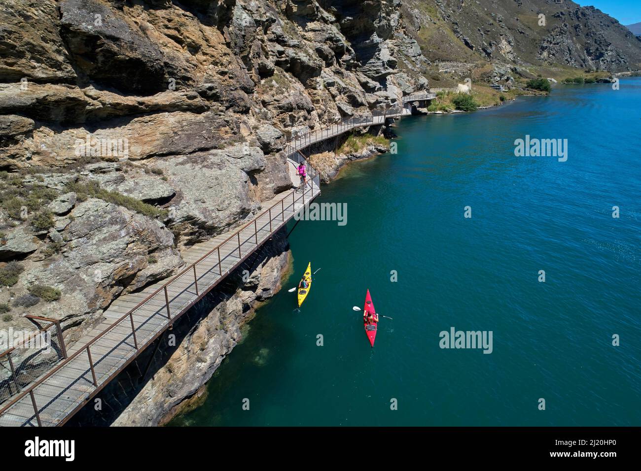 Cyclists on cantilever bridge on Lake Dunstan Cycle Trail, and kayakers, Lake Dunstan, near Cromwell, Central Otago, South Island, New Zealand - drone Stock Photo