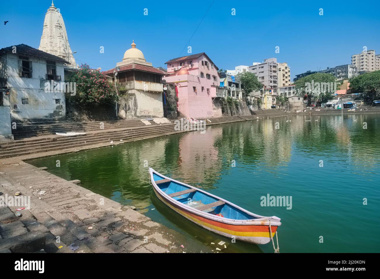 A small rowing boat is anchored in Banganga Tank, a sacred Hindu spot  surrounded by several Hindu temples, in Walkeshwar area, Mumbai, India Stock Photo