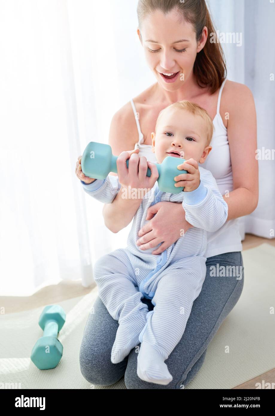 Whats your superpower. Shot of a young woman working out while spending time with her baby boy. Stock Photo