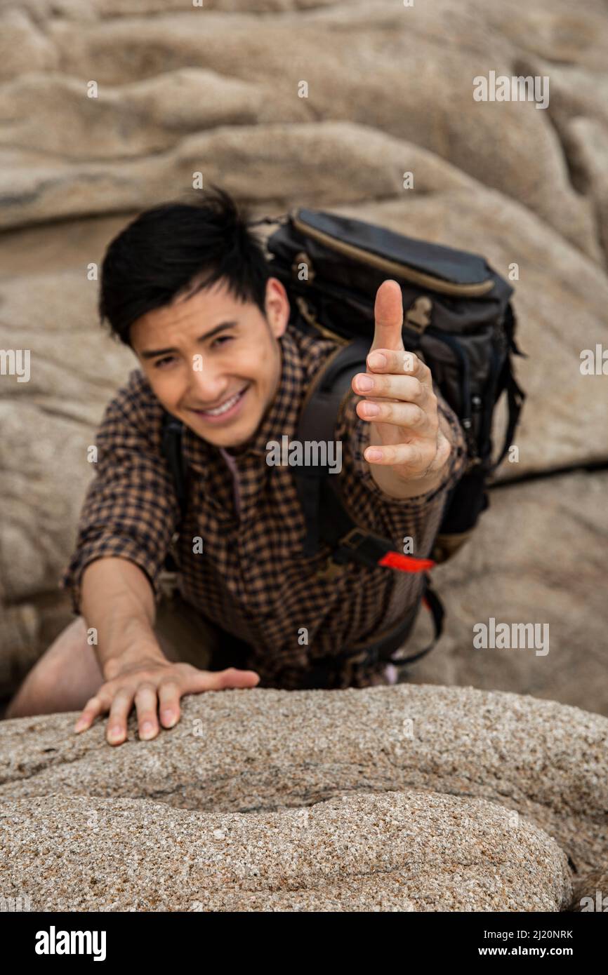 Climber reaching out to his partner for help - stock photo Stock Photo
