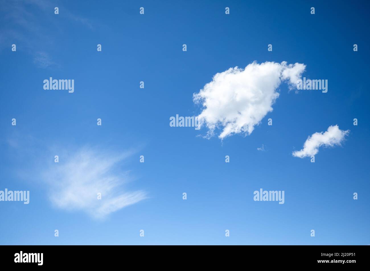 Three contrasting clouds in a bright blue sky Stock Photo