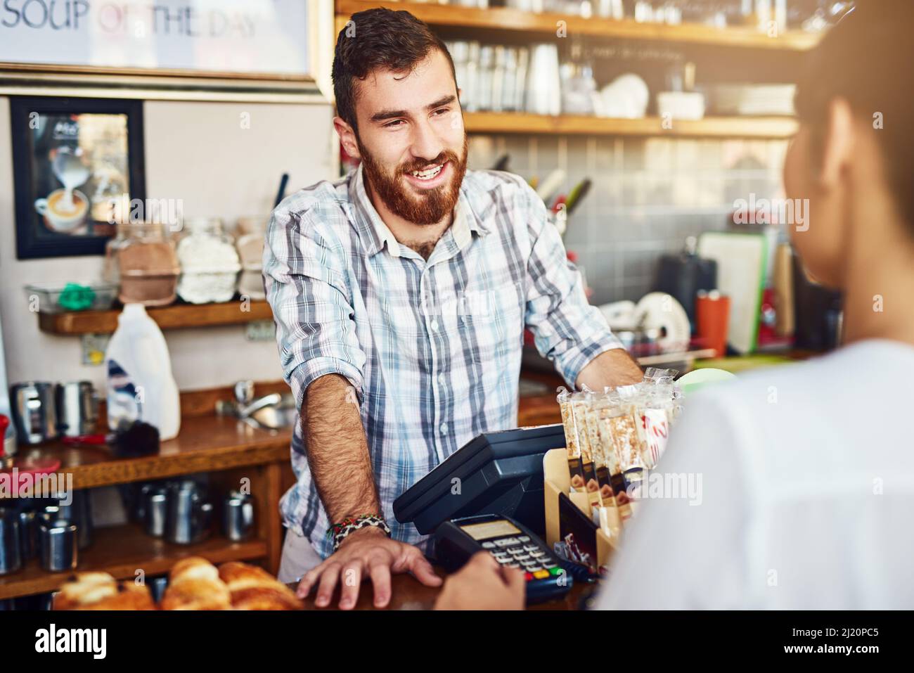 Good customer service is what makes them come back. Shot of a shop assistant helping a customer in a cafe. Stock Photo