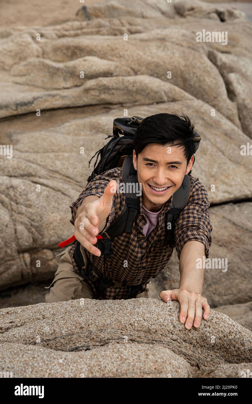Climber reaching out to his partner for help - stock photo Stock Photo