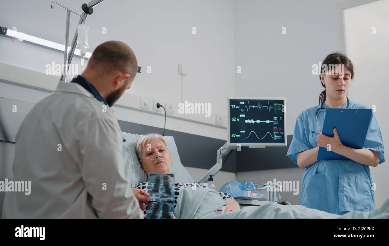 Doctor showing diagnosis of radiography to patient with illness laying ...