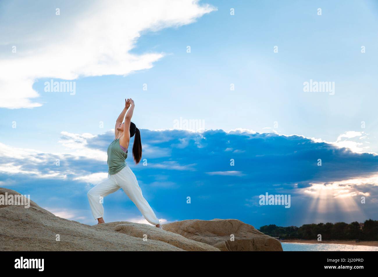 Beautiful young lady practicing yoga on the beach reef - stock photo ...