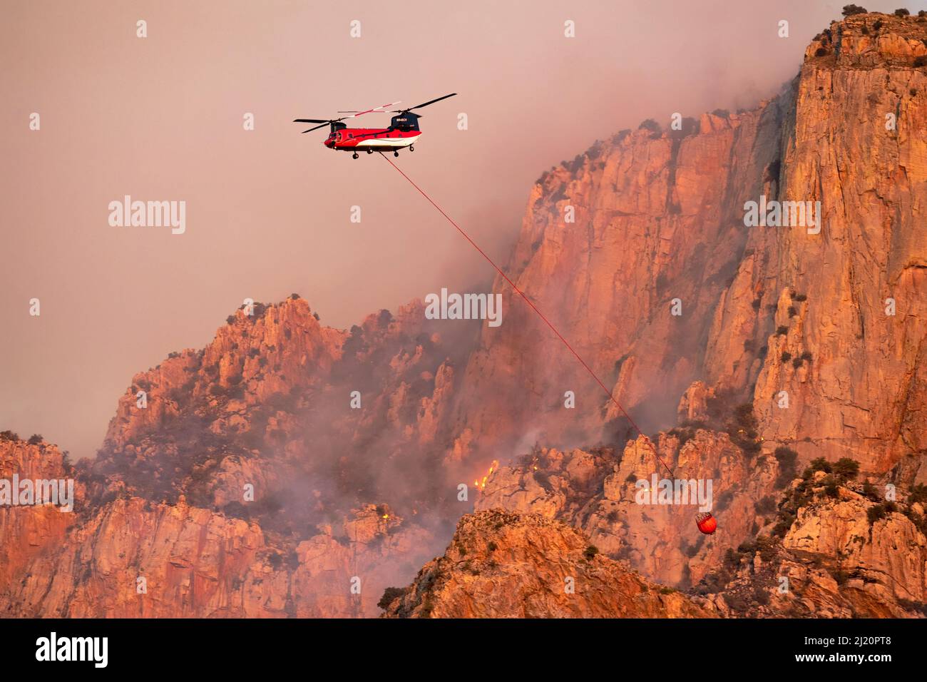 Lightning started fire on steep craggy terrain,  with  US Forest Service Fire suppression Wildland Firefighters using helicopters to 'bomb' the hot sp Stock Photo