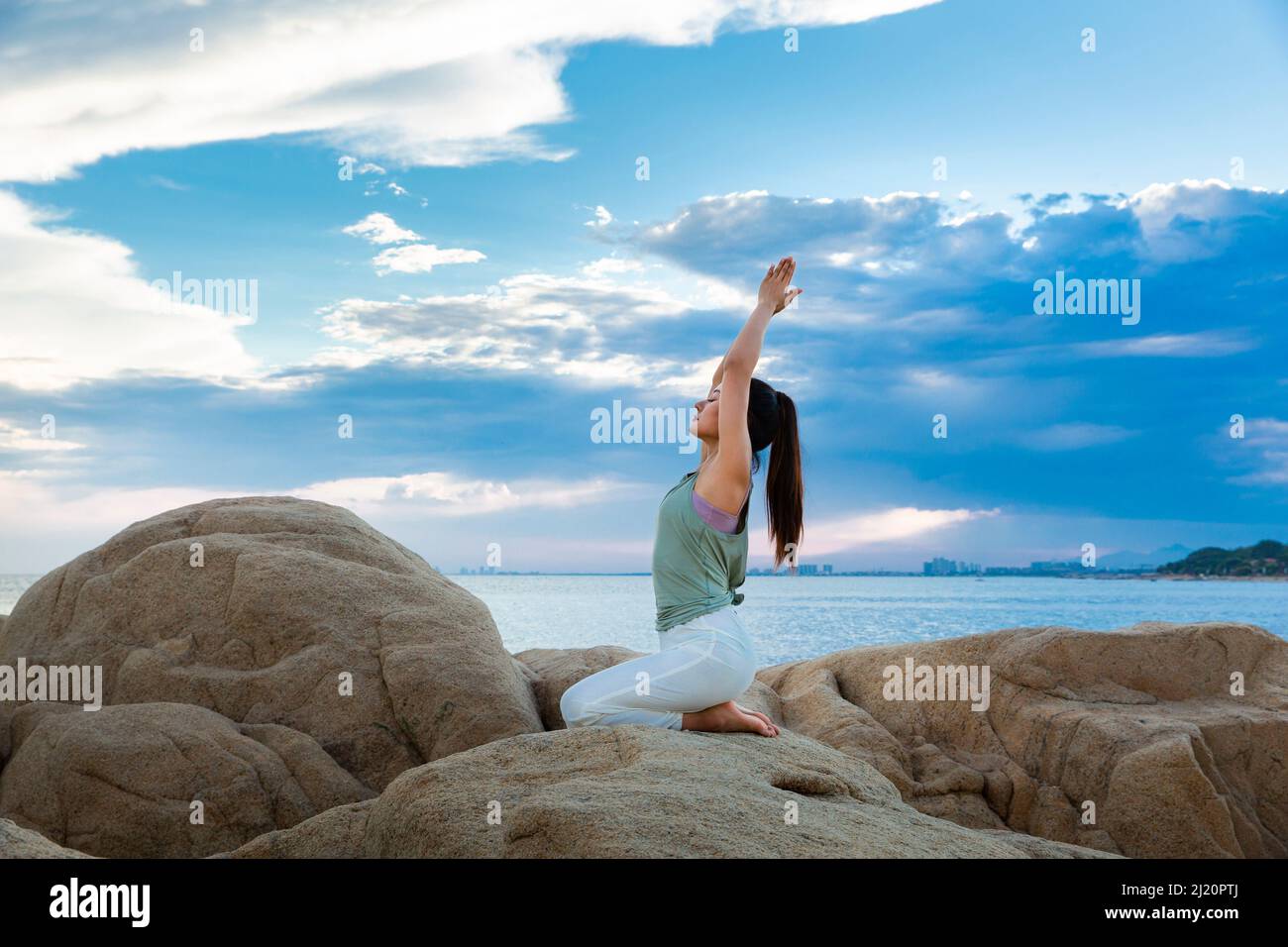 Beautiful young lady practicing yoga on the beach reef - stock photo ...