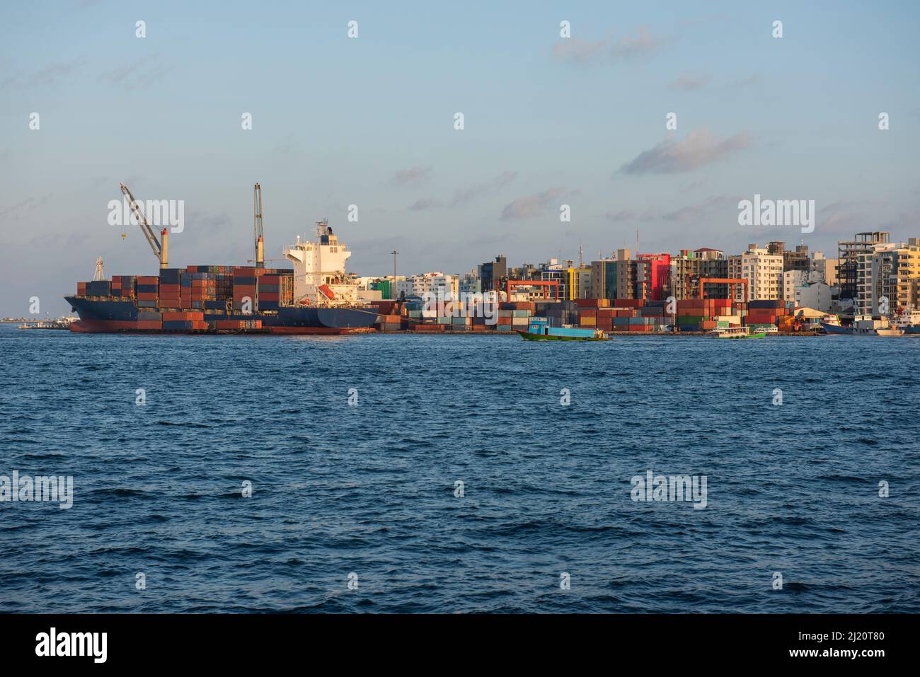 Large container ship moored in commercial industrial shipping port on island city in open ocean Stock Photo