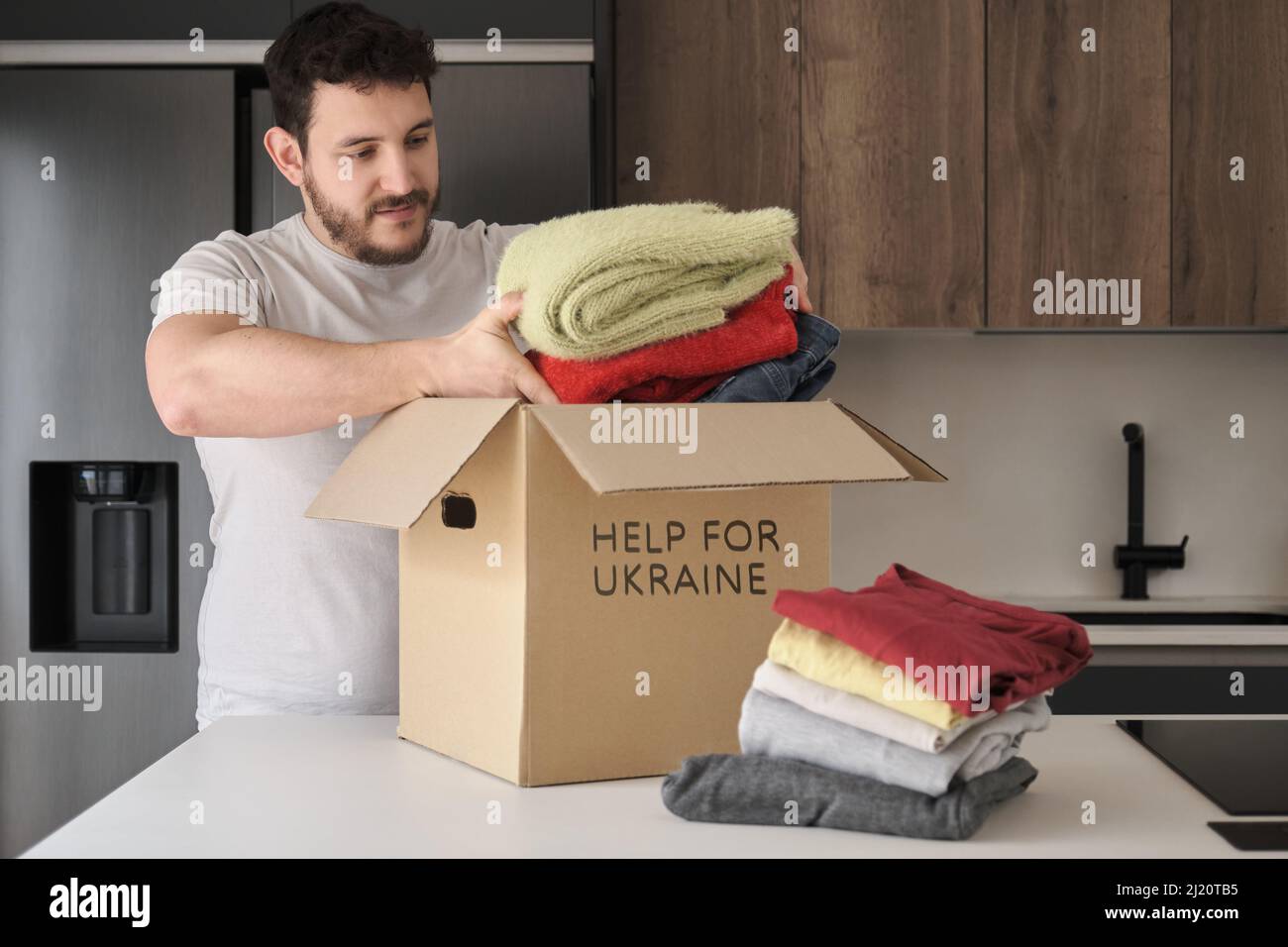 Volunteer filling donation box with clothes to help ukrainian refugees