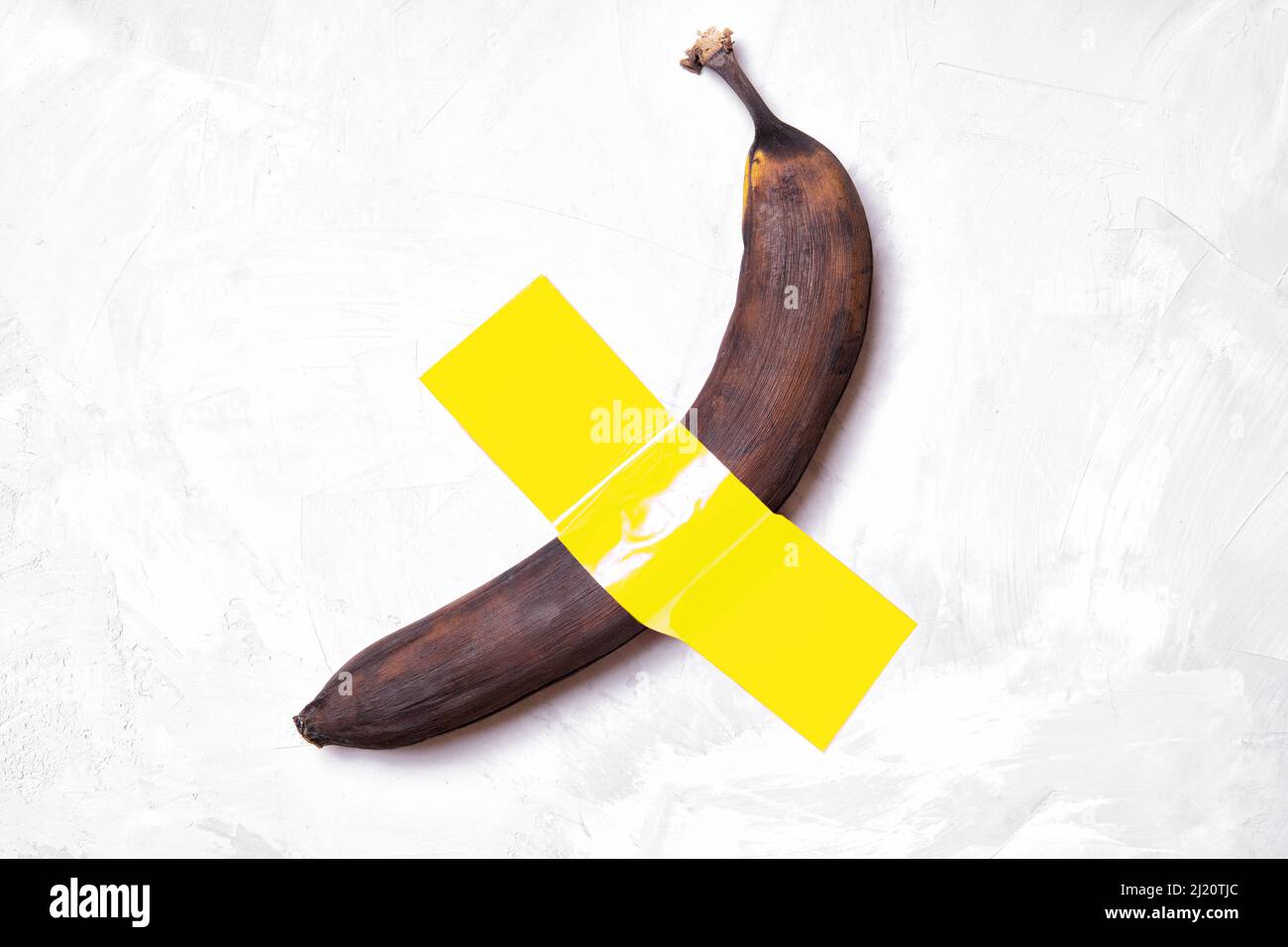 Brown banana affixed to a concrete wall with a yellow ducttape Stock Photo Alamy
