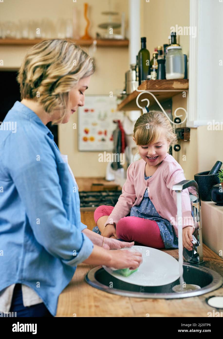 Teaching her daughter the domestic basics. Shot of a cheerful young mother and her young little daughter washing dishes together at home. Stock Photo