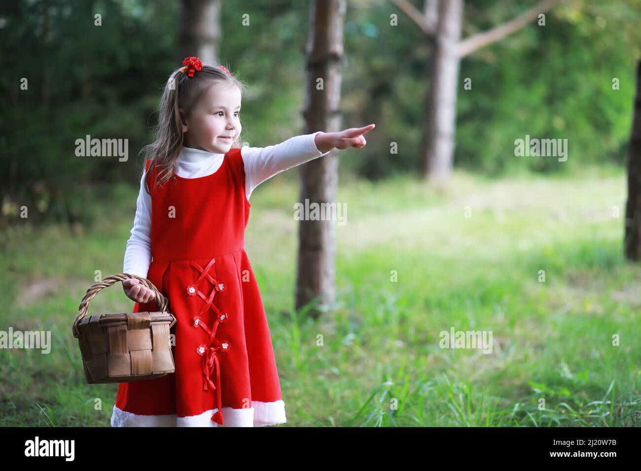 A little girl in a red hat and dresses is walking in the park. Cosplay ...