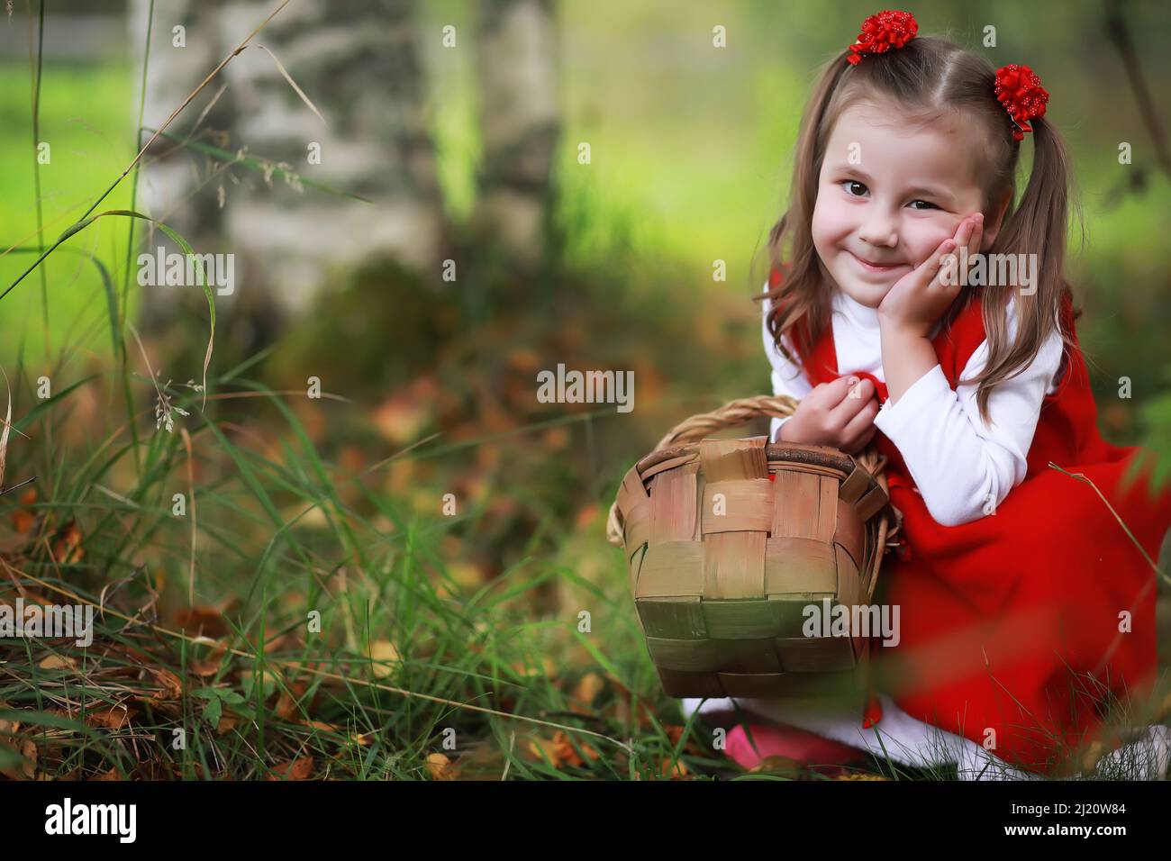 A little girl in a red hat and dresses is walking in the park. Cosplay ...