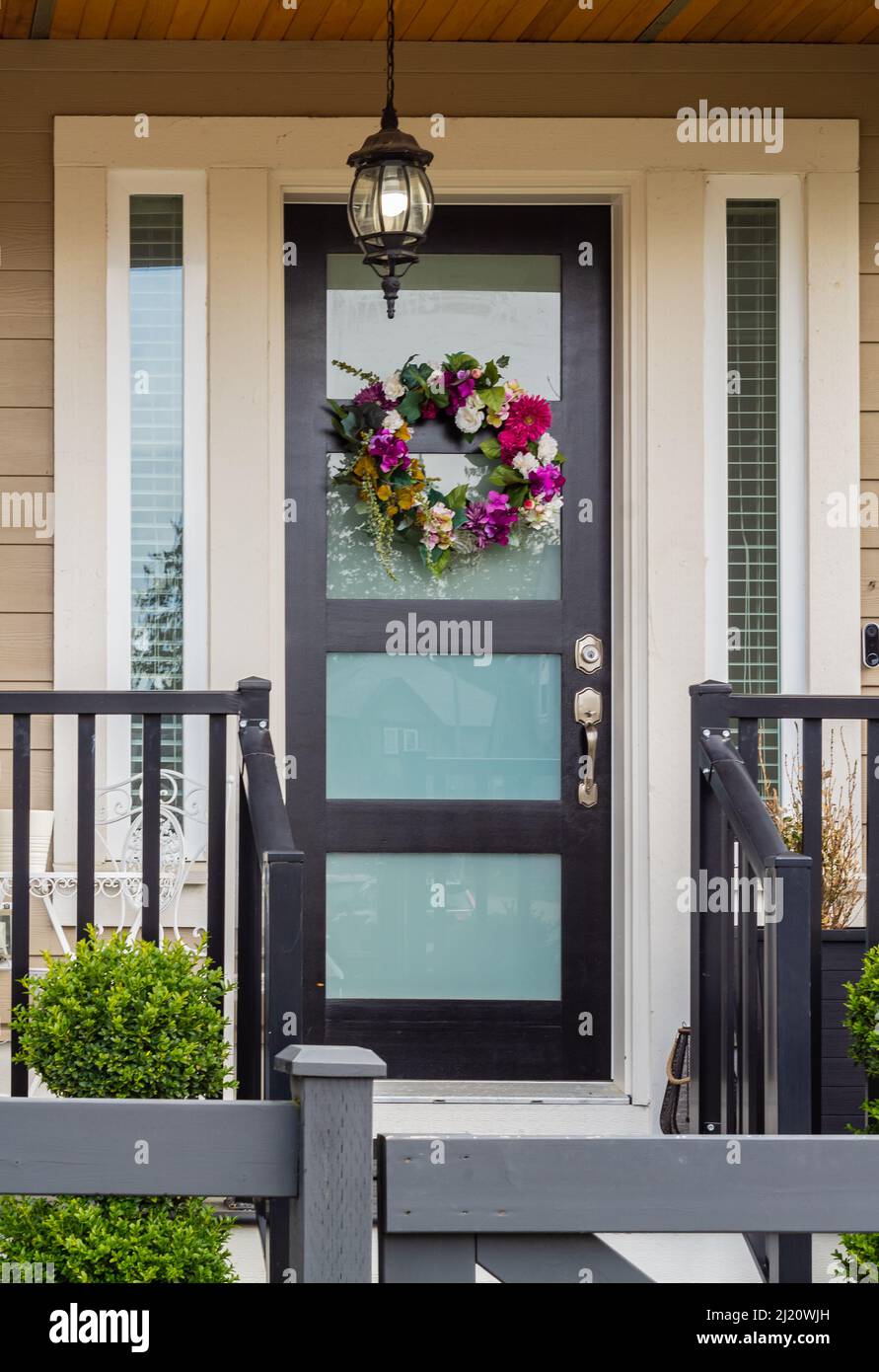 Flower wreath. Spring decoration on the door of the house. Exteriror of a house. Entrance of a nice single family house. Nobody, selective focus, stre Stock Photo