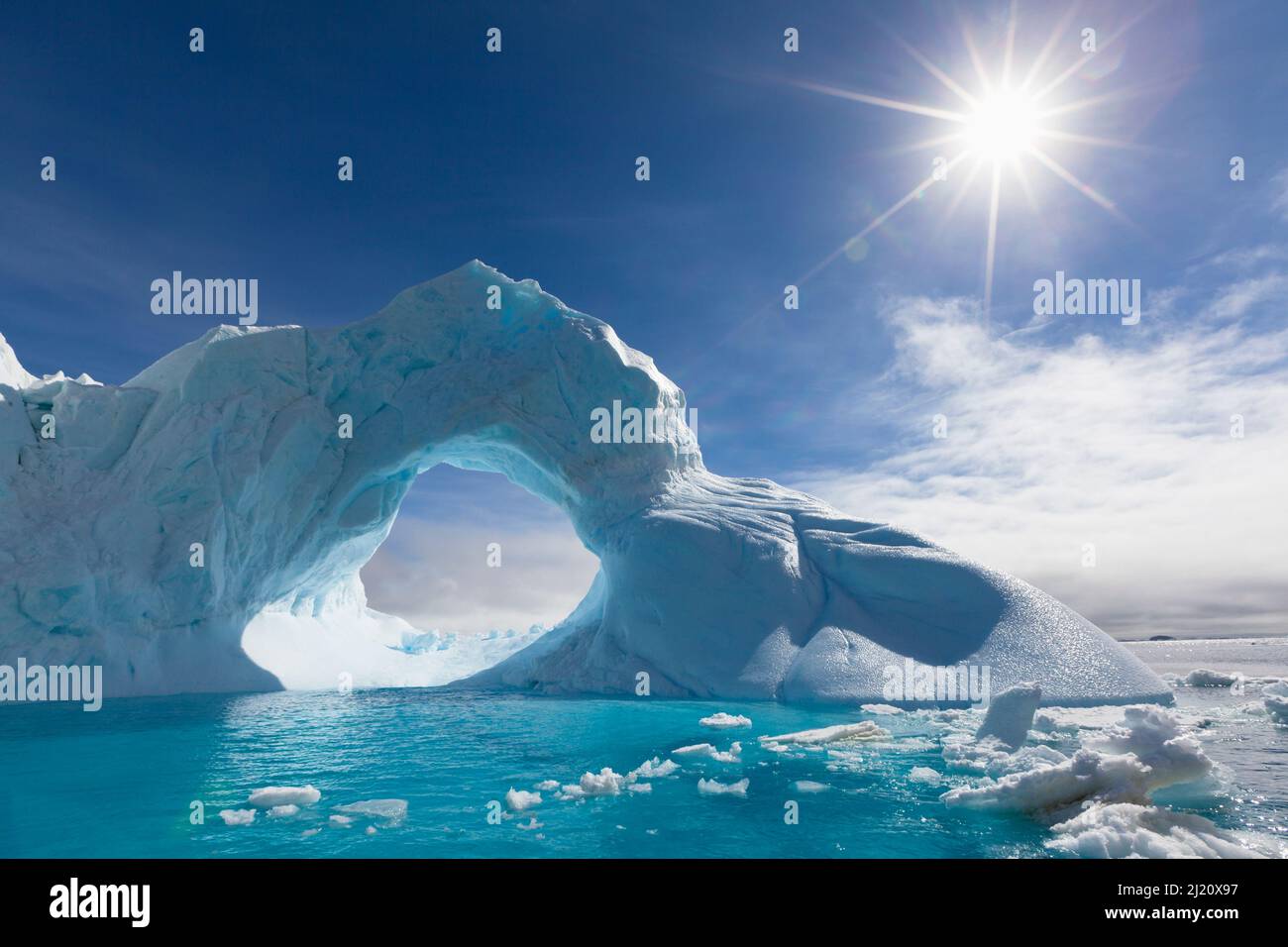 Iceberg Arch and sunstar along the Antarctic Sound, Antarctica. Stock Photo