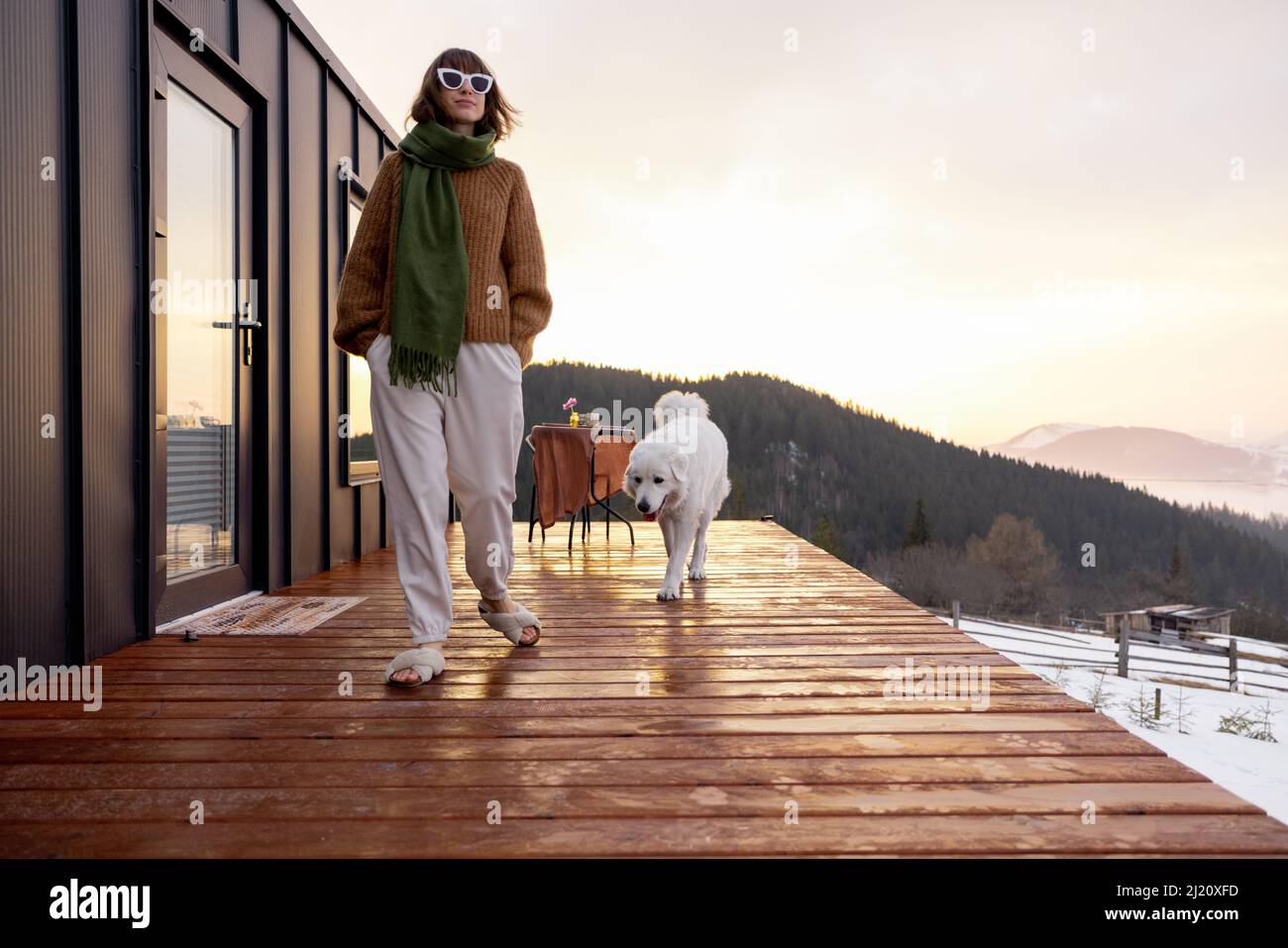 Woman with her dog resting on terrace of tiny house on nature Stock ...