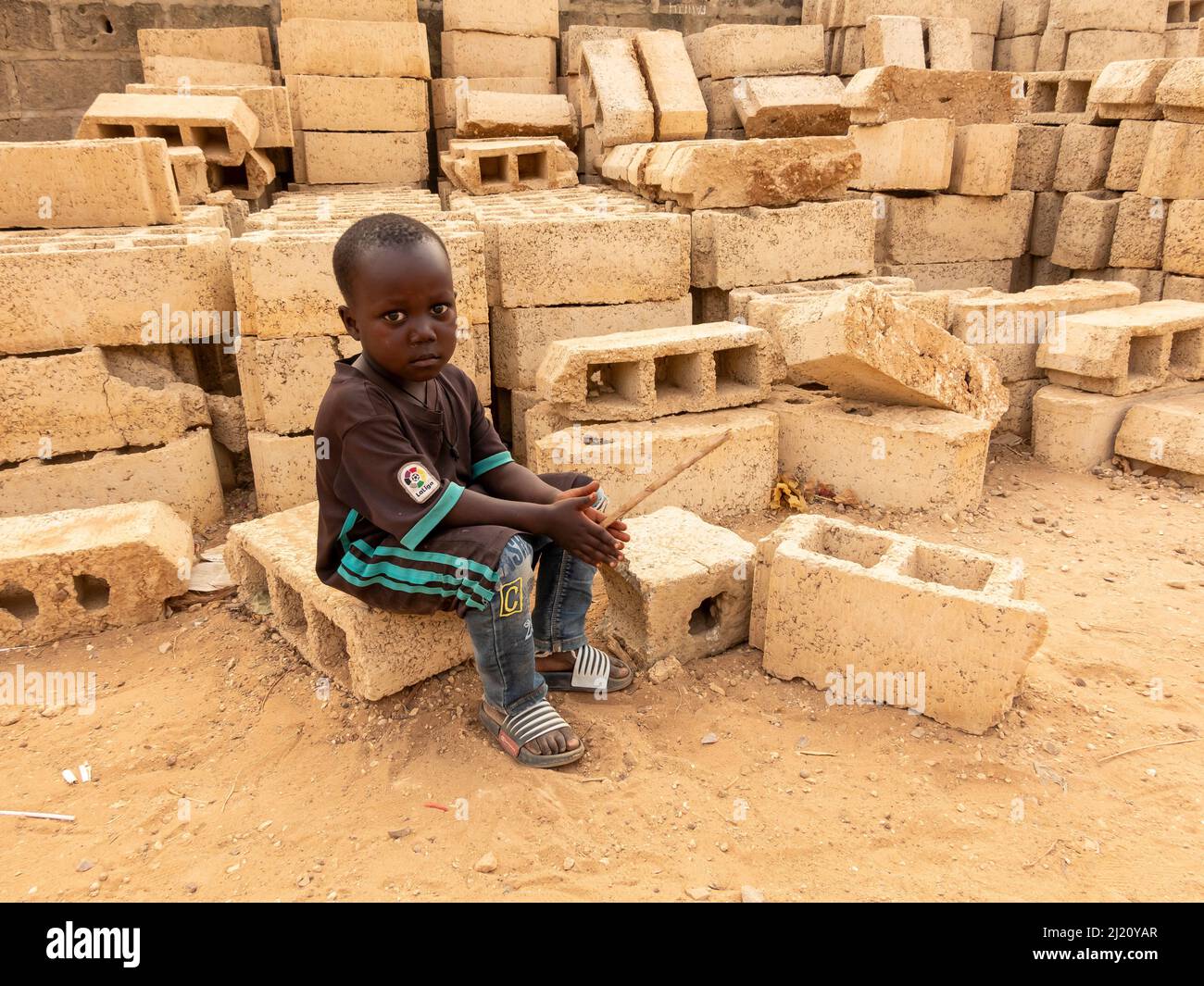MBOUR, SENEGAL, AFRICA - DECEMBER Circa, 2021. Unidentified young african child sitting in street, looking so sad and poor. Poverty in Africa and diff Stock Photo