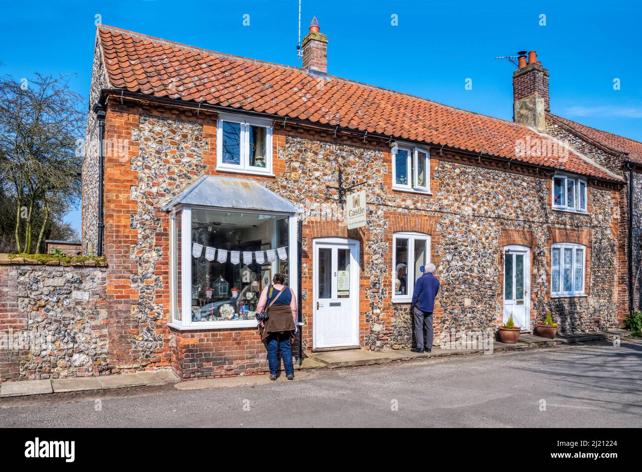 People looking in the windows of Castle Antiques and Collectables antique shop in Castle Acre, Norfolk. Stock Photo