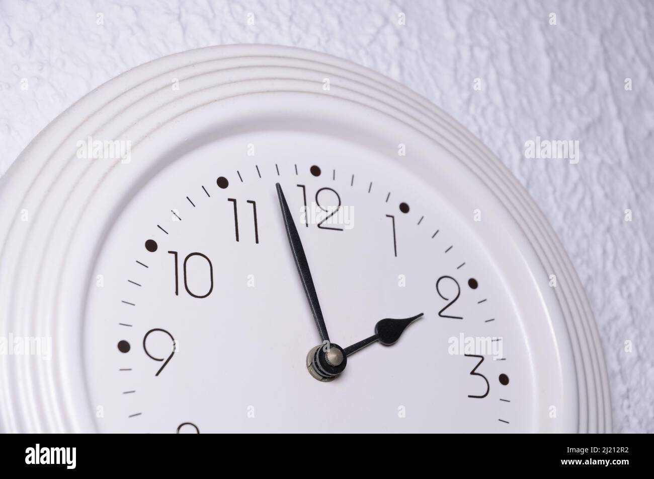White clock with black clock hands on a wall indoors Stock Photo Alamy