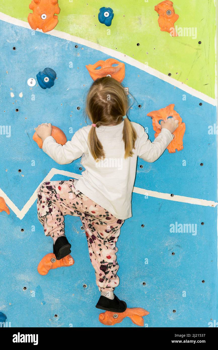 Young girl climbing and bouldering on a wall Stock Photo