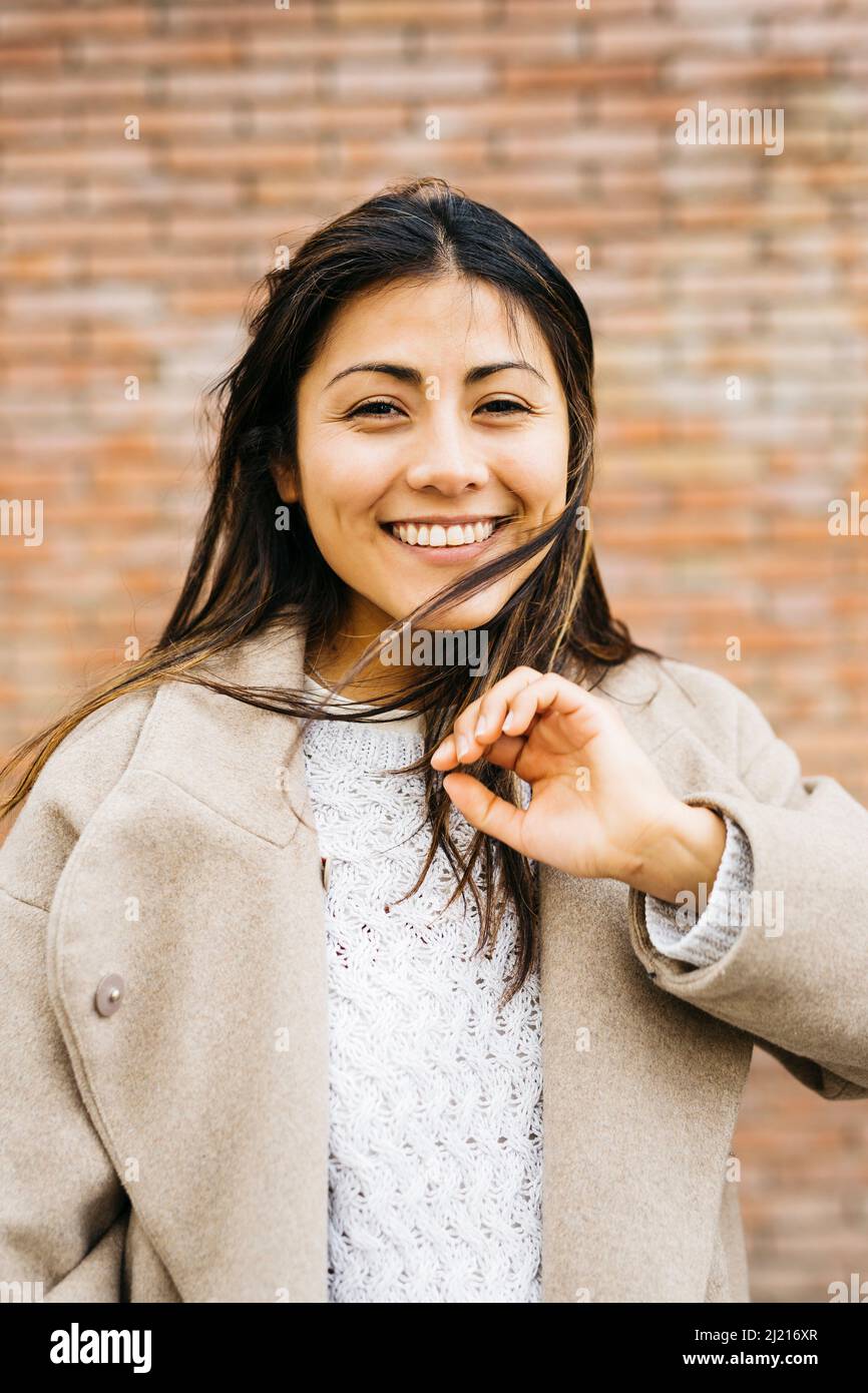 Portrait of a young woman against a brick wall Stock Photo