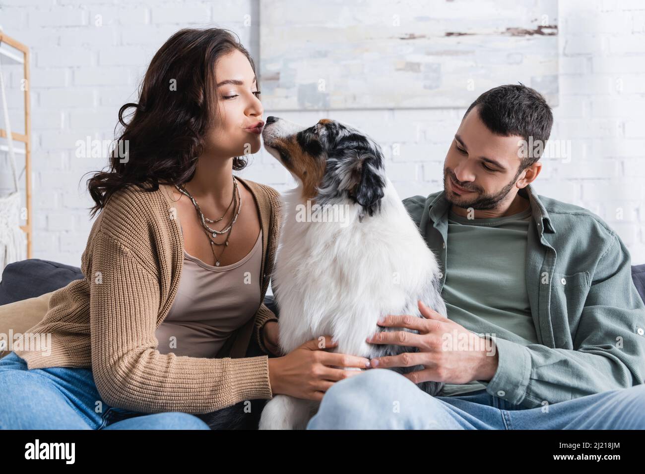 young woman kissing australian shepherd dog near happy boyfriend Stock  Photo - Alamy