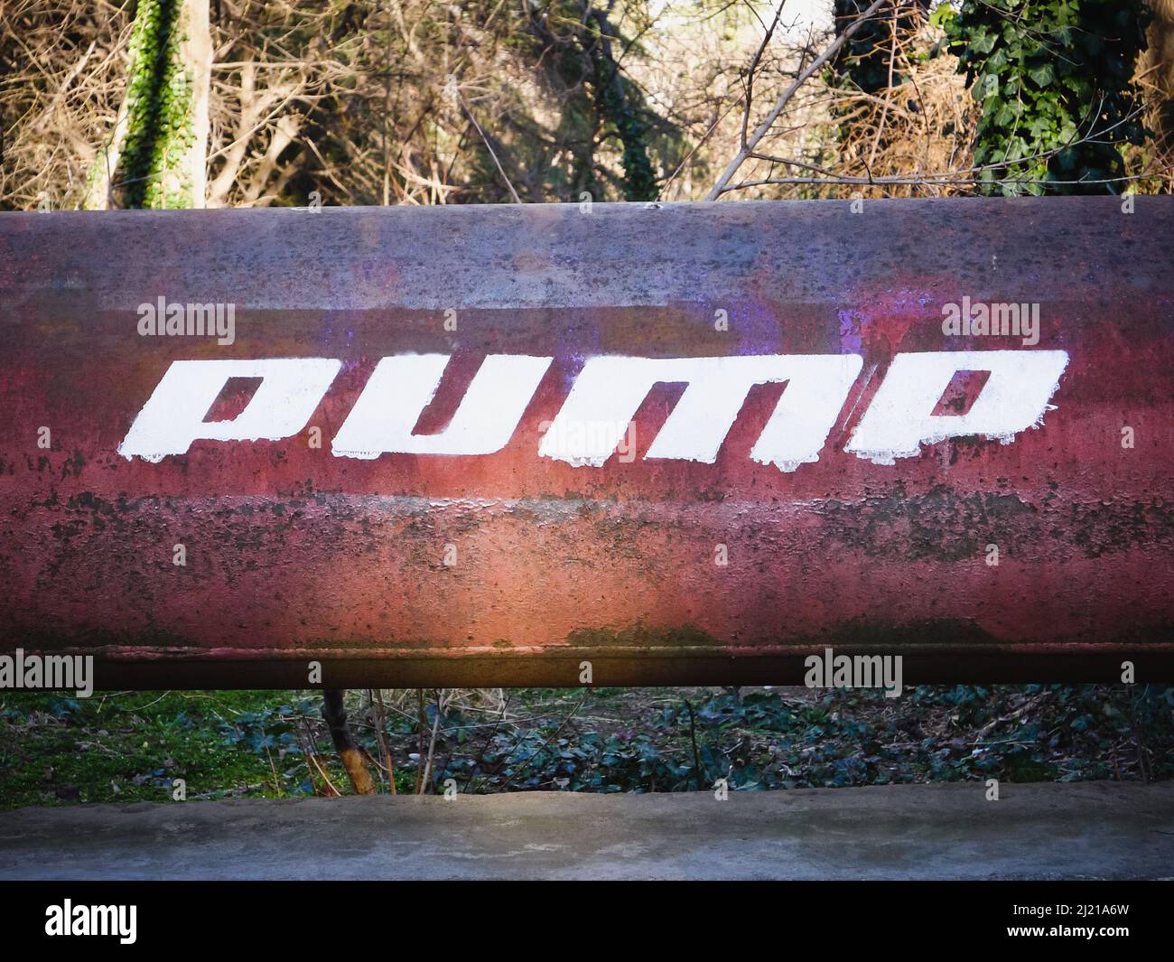 Rusty iron pipe with white text. Word PUMP written on a pipe. Stock Photo
