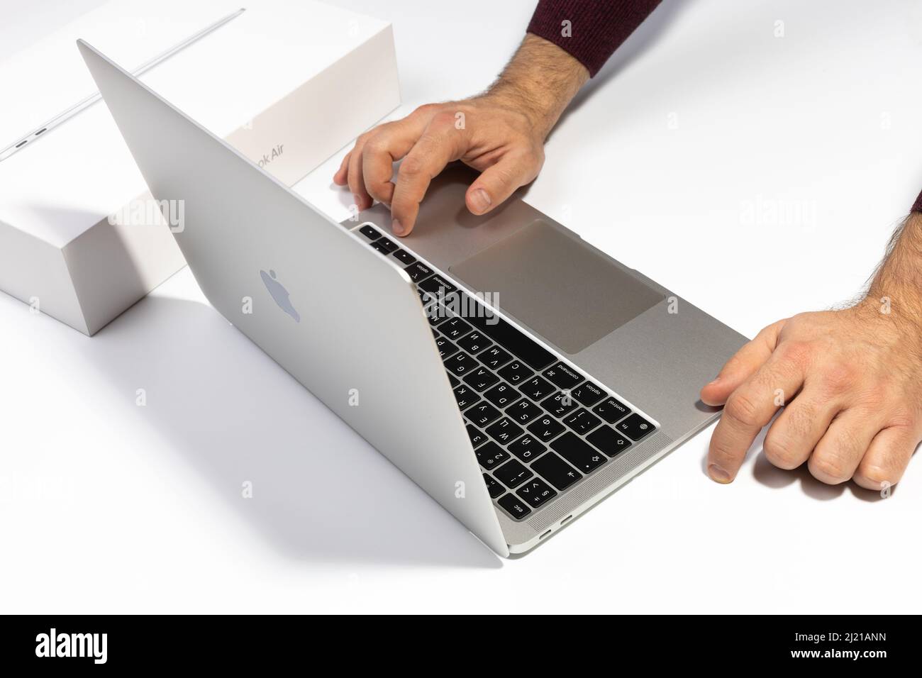 Saratov, Russia - February 26, 2022: turn on Macbook Air 13 inch with M1 processor. Unpacking new Apple laptop closeup, white background. Advertising Stock Photo