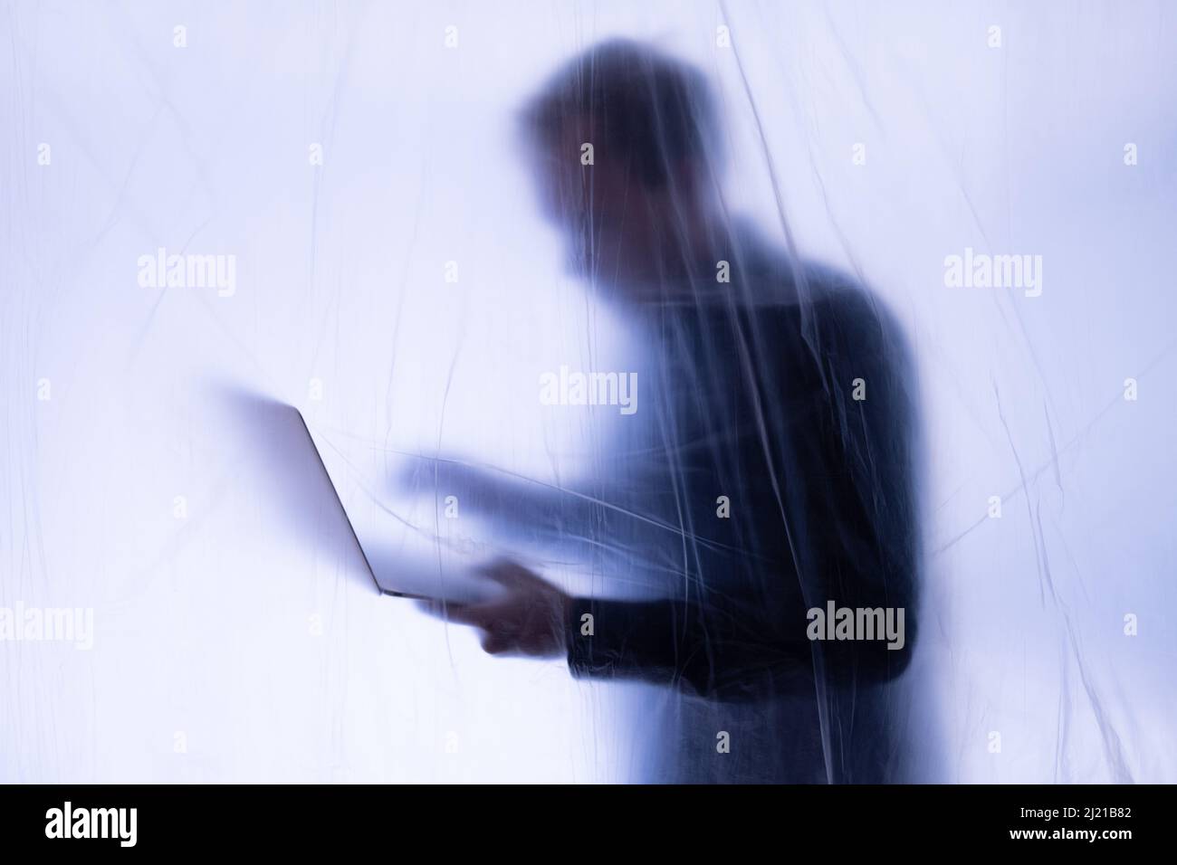 Anonymous Hacker commits cyber crime with laptop held in hand Stock Photo