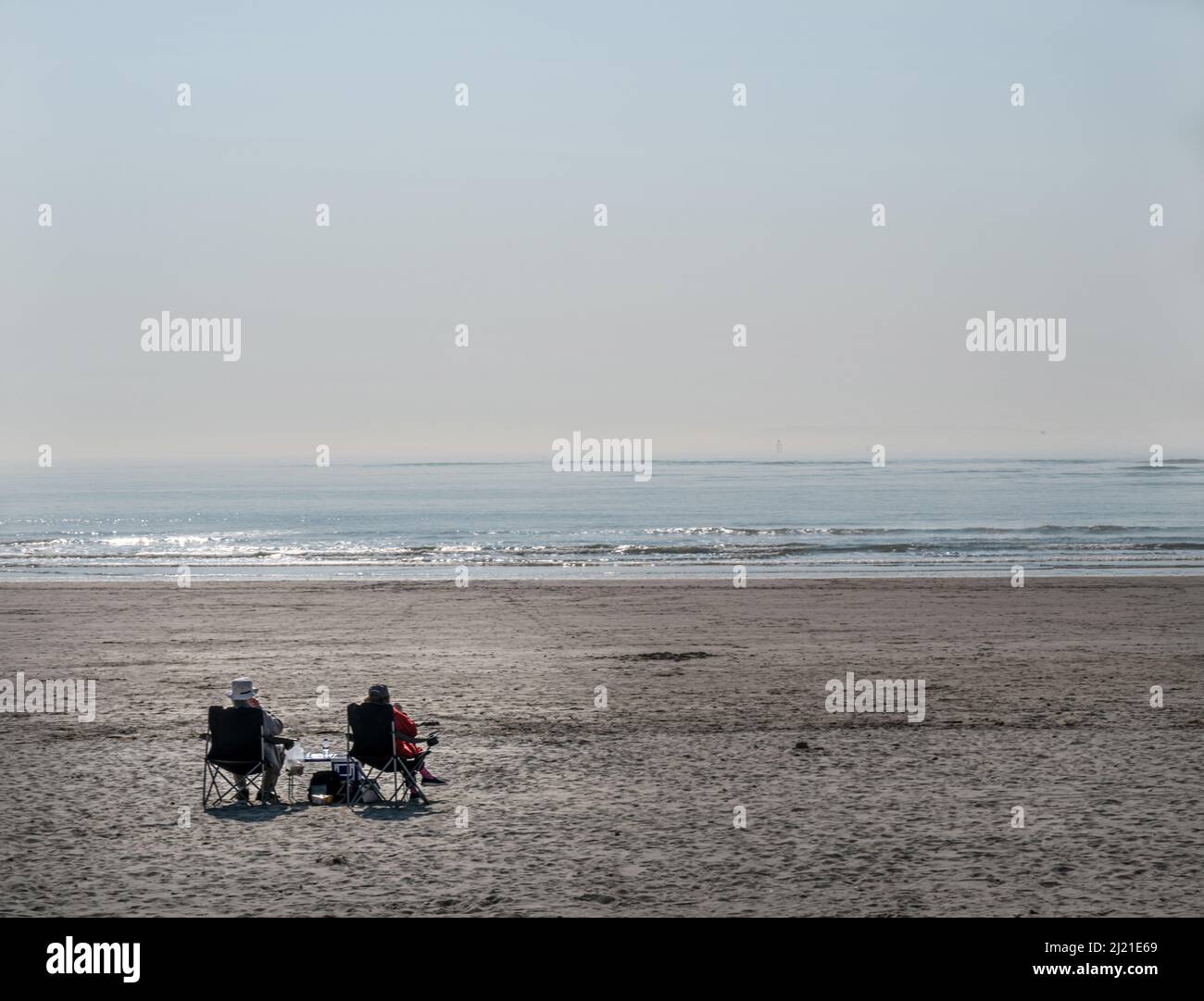 Couple sitting on beach facing the sea Stock Photo - Alamy