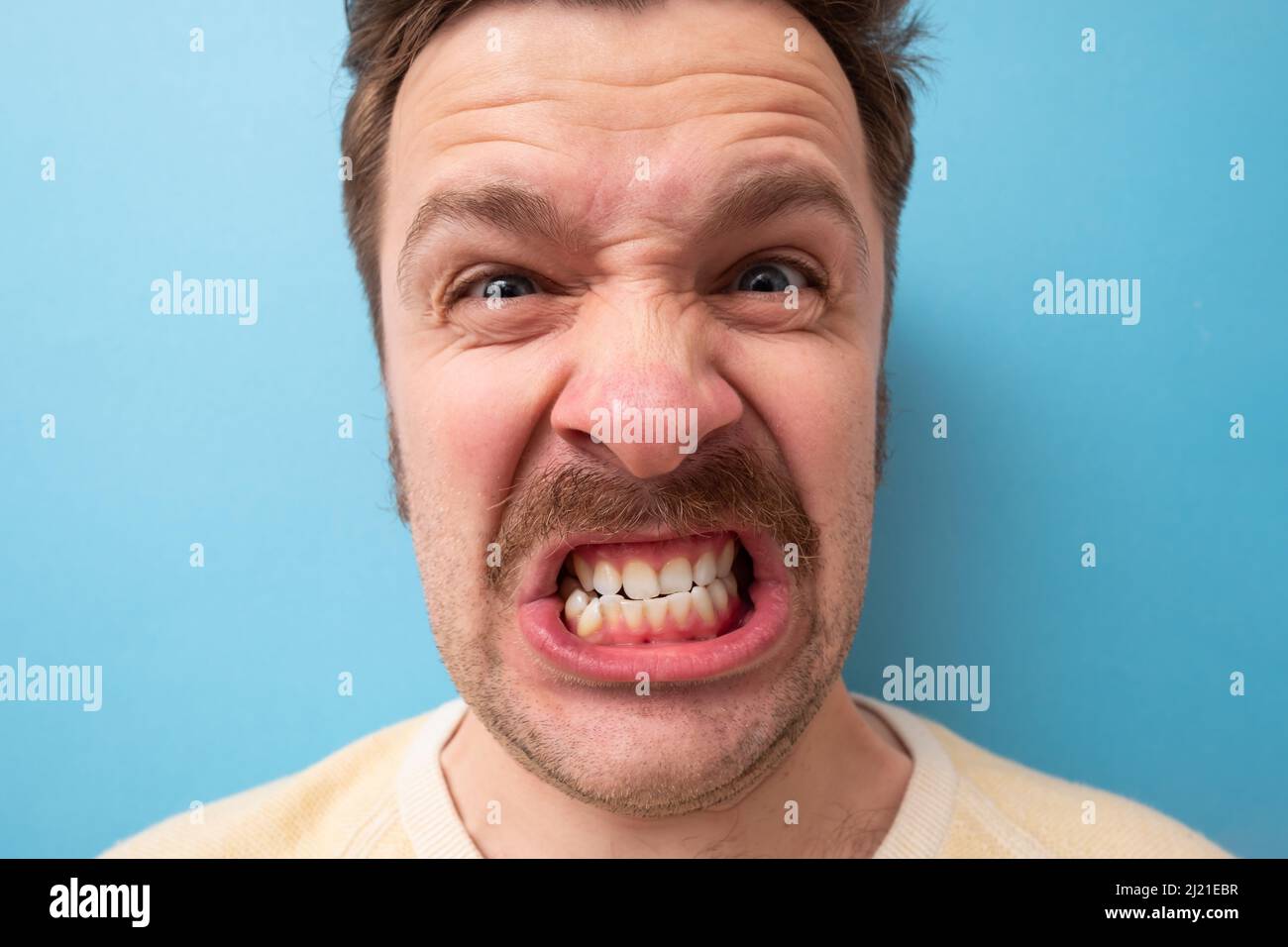 Caucasian man with mustache shouting being angry and furious. Stock Photo