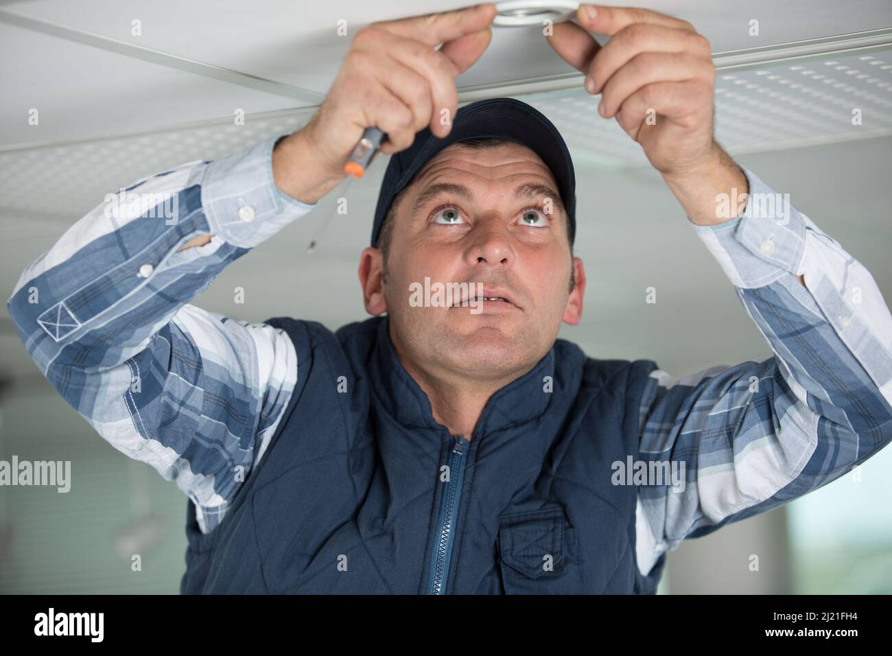 an electrician is repairing the ceiling light Stock Photo - Alamy