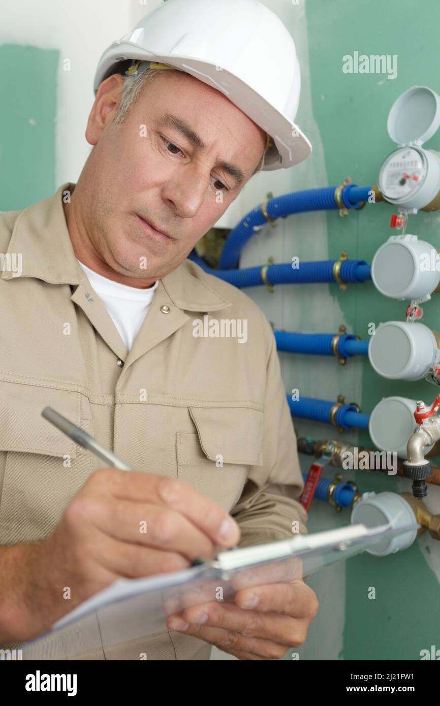 senior plumber writing on clipboard Stock Photo