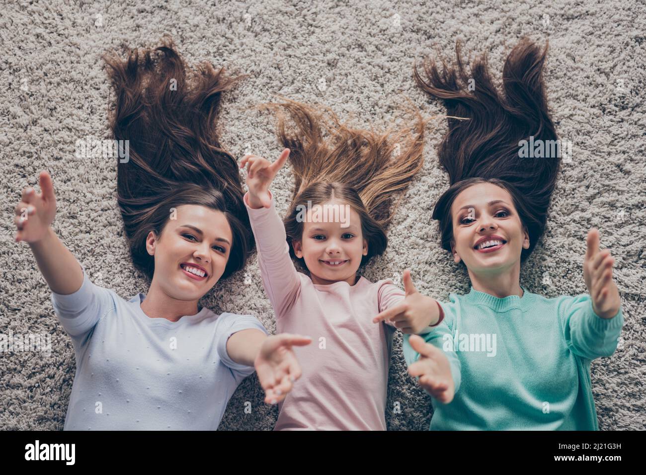 Top above high angle view portrait of attractive cheerful family lying on carpet hugging calling you at home indoors Stock Photo