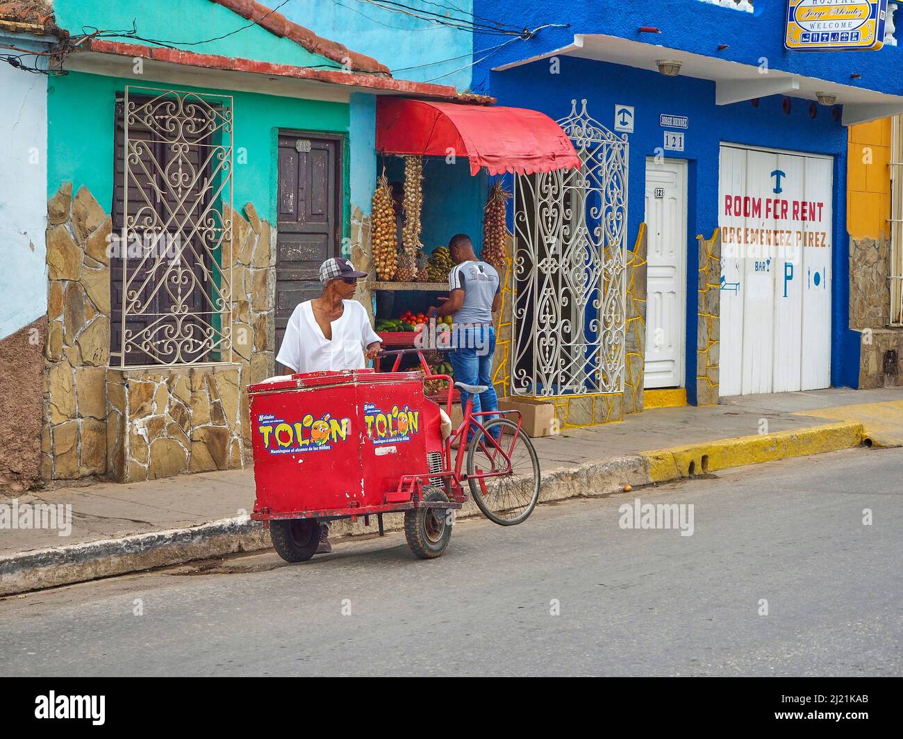 Iceman waits for customers, in the back a small shop for fruits and vegetables, Cuba, Sancti Spiritus, Trinidad Stock Photo