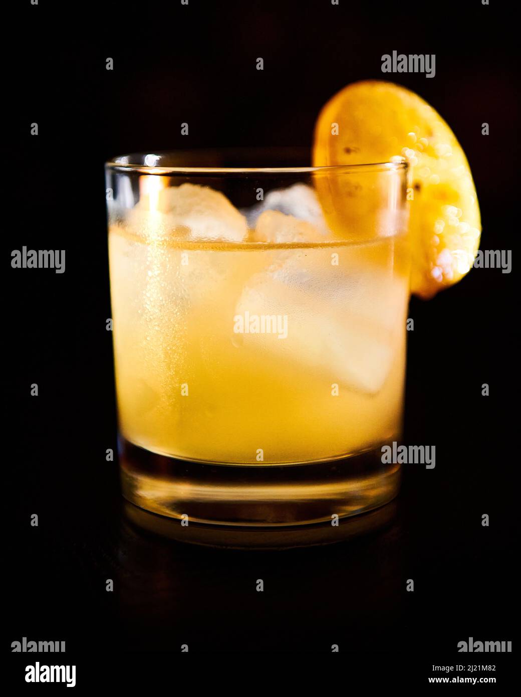 A custom cocktail between a penicillin and a rusty nail with notes of honey lemone and whisky. Yellow in colour with a slice of lemon. Stock Photo