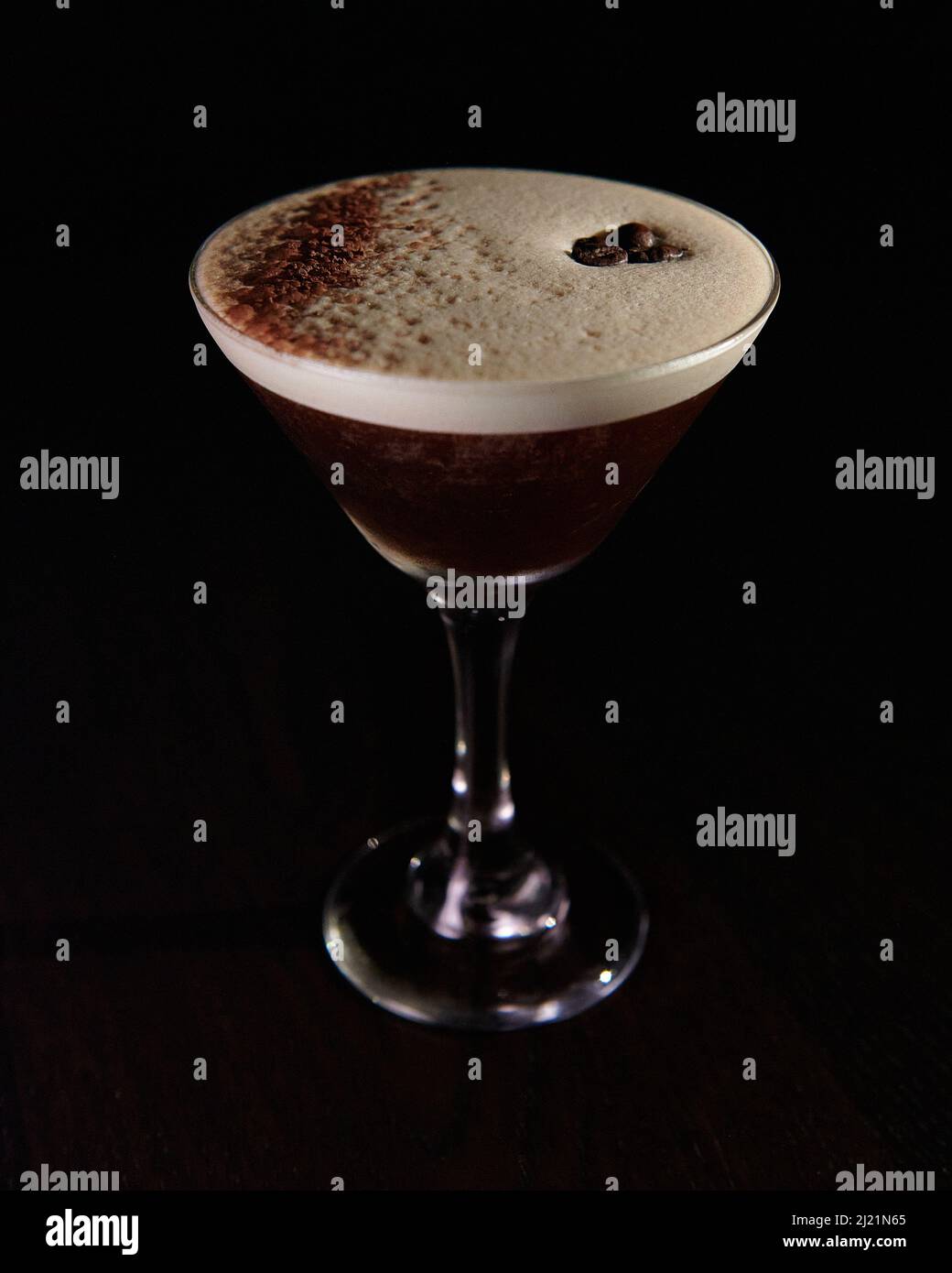 A foamy espresso martini, topped with coffee beans and chocolate dust