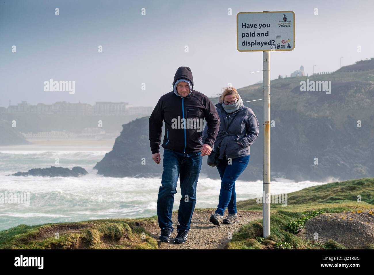 People walking along the coast path in strong storm force winds brought by Storm Eunice as it batters the coastline around Newquay in Cornwall. Stock Photo