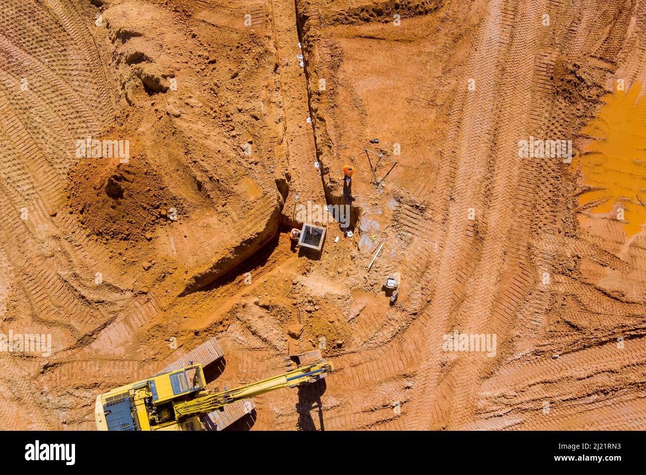 Aerial top view of construction site laying concrete pipe drainage system with working industrial machines Stock Photo