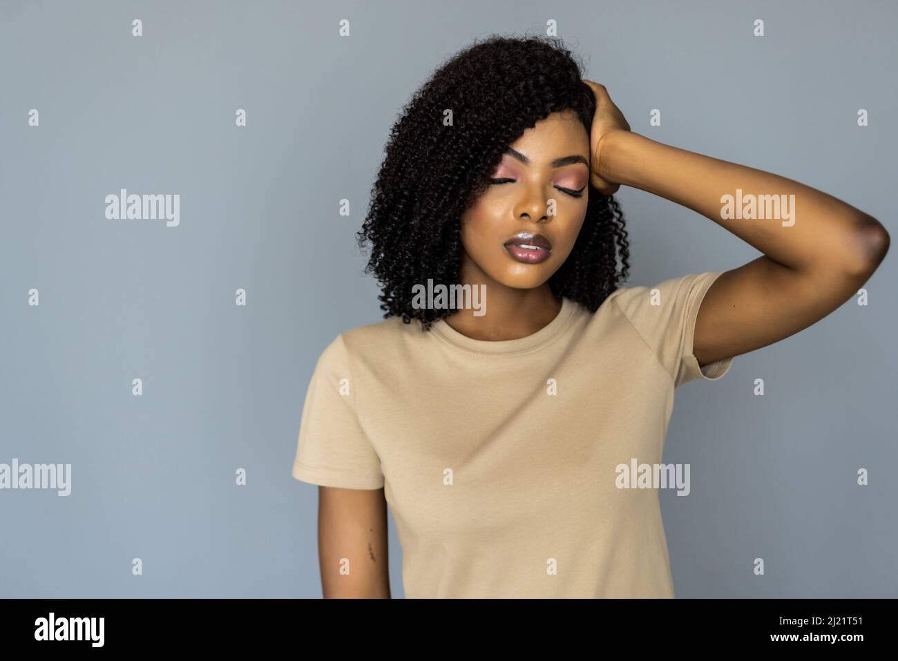 Studio portrait on grey blank, stressful young unhappy unhealthy african female closed her eyes suffering from strong chronic daily headache, touching Stock Photo