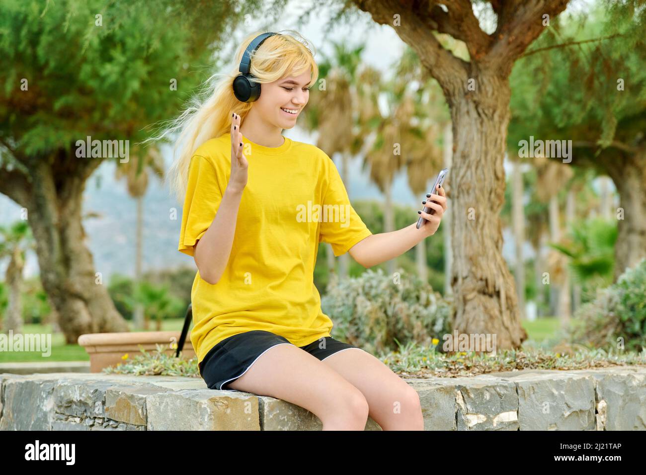Hipster teenage girl in headphones with smartphone talking on video ...