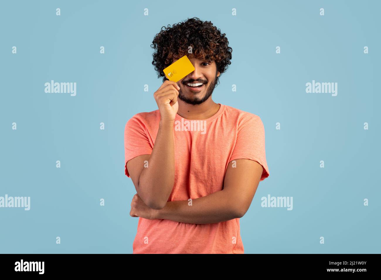 Curly indian guy covering eye with credit card Stock Photo - Alamy