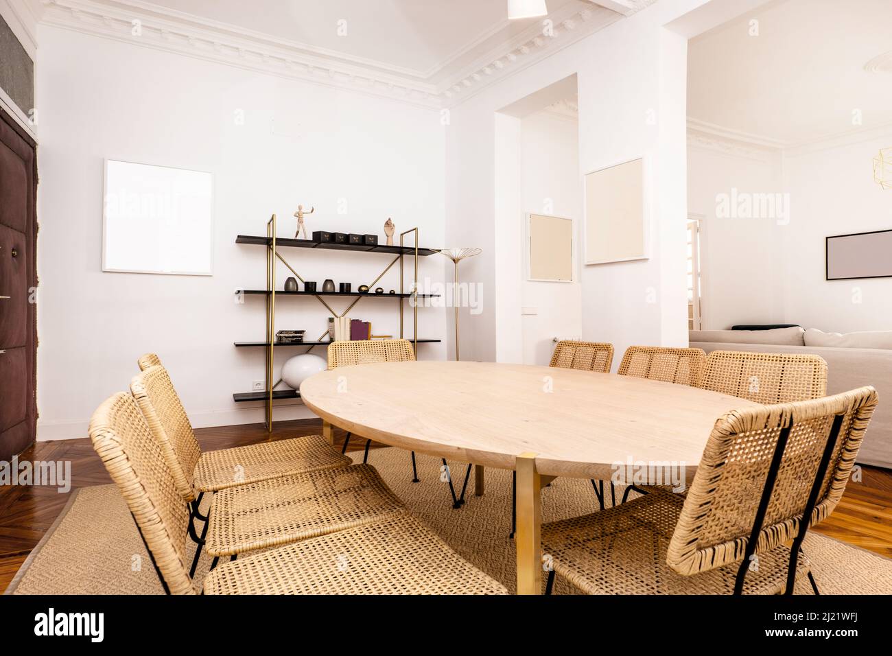 Living room with oval wooden dining table, wicker chairs and wall shelf