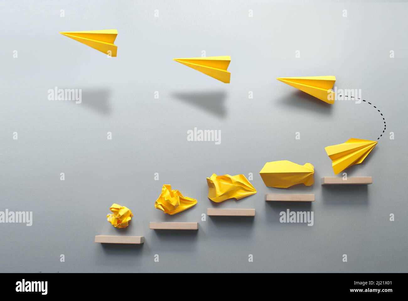 Wooden steps with different stages of making a paper airplane, before taking flight, creating something from nothing success concept Stock Photo
