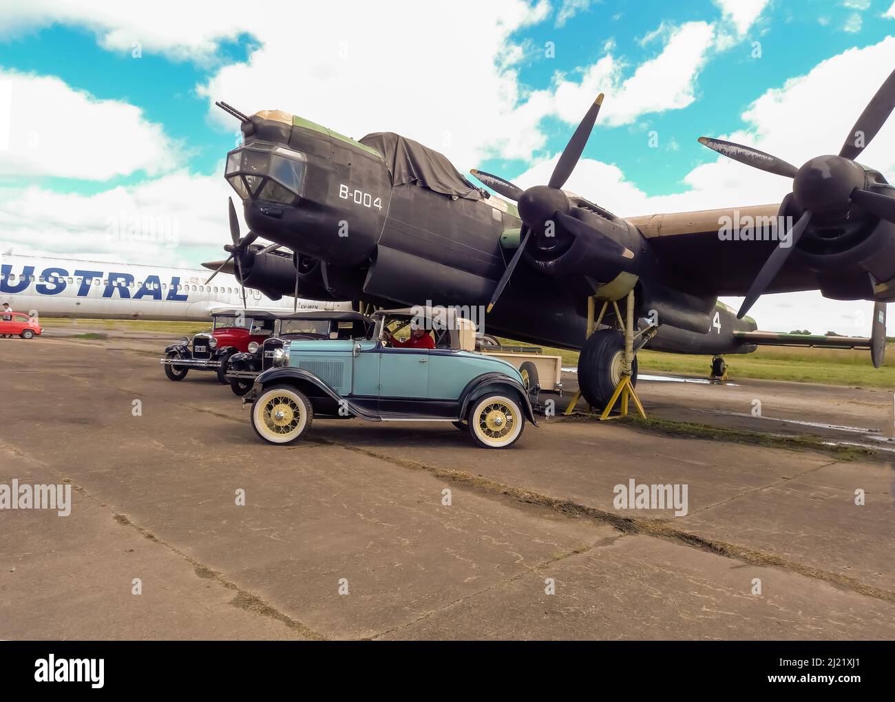 Old cyan Ford Model A coupe roadster circa 1930 parked in front of a WWII Avro Lincoln MKII four-engined bomber 1944-1967. Classic car show. Copyspace Stock Photo