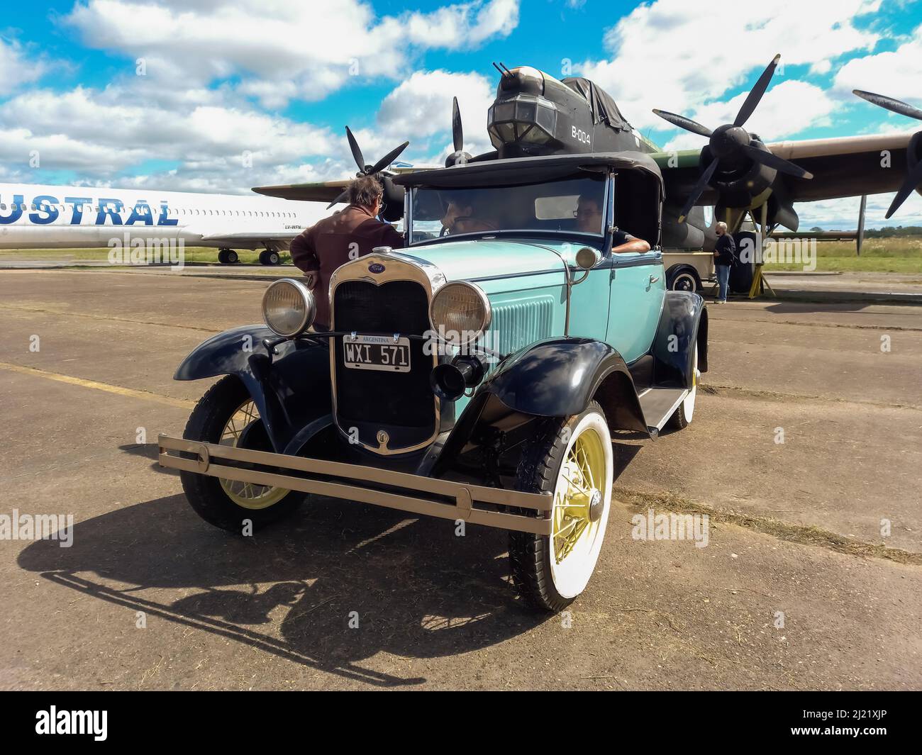 Old cyan Ford Model A coupe roadster circa 1930 parked in front of a WWII Avro Lincoln MKII four-engined bomber 1944-1967. Classic car show. Copyspace Stock Photo