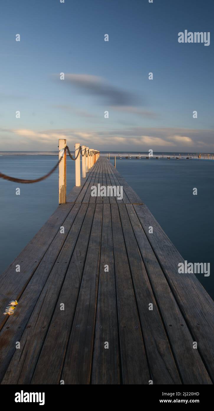 A vertical shot of a wooden jetty leading to the water of the sea Stock ...