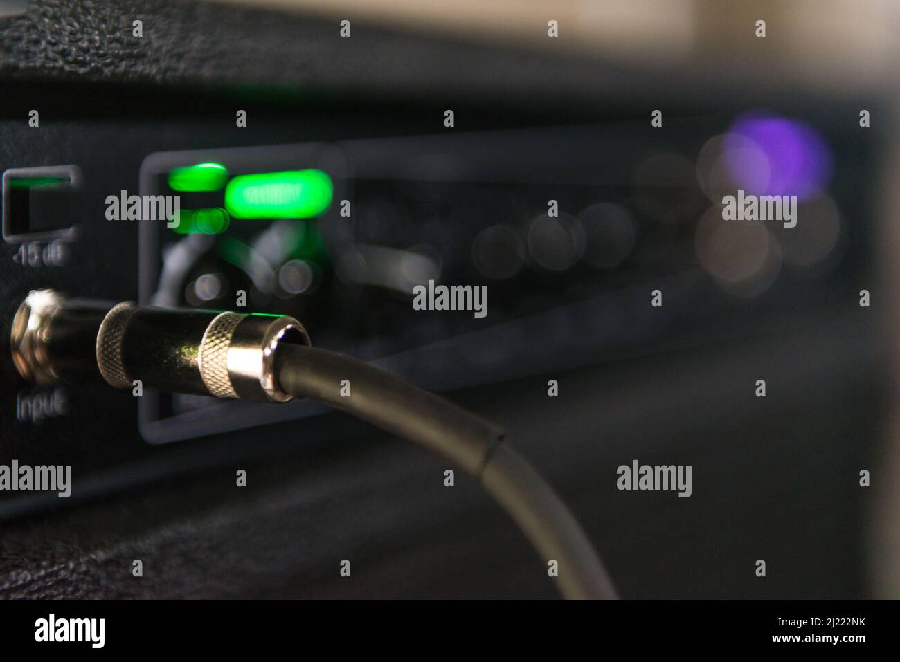 Cable from a bass connected to the amp where you can see some lights and knobs to control the