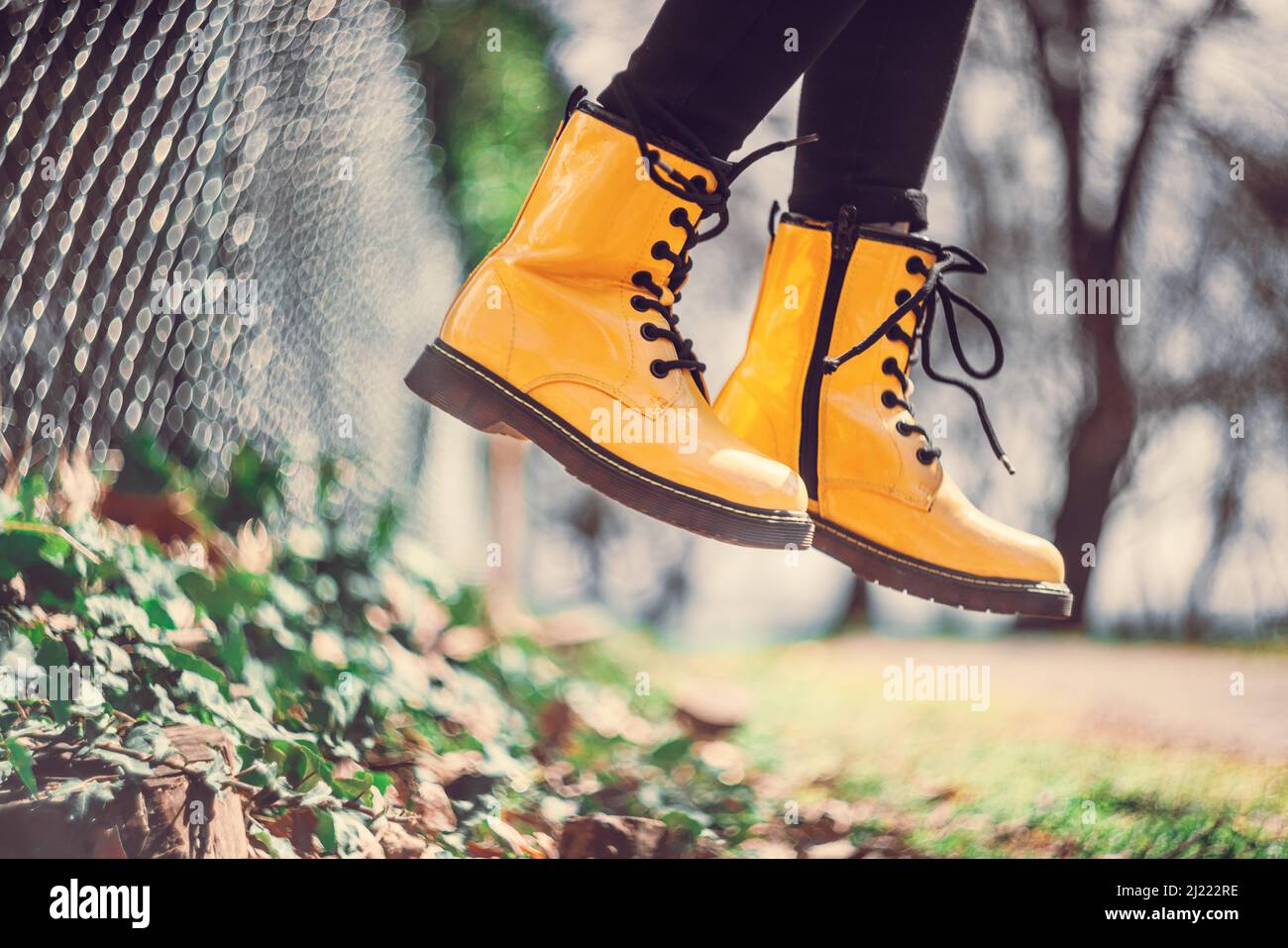 Yellow boots of a jumping girl in green grass outdoor, defocus bokeh with vintage lens Stock Photo